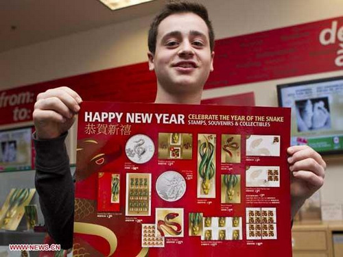 A boy shows a poster including all stamps and collectibles of the Year of the Snake at a post office in Toronto, Canada, Jan. 8, 2013. (Xinhua/Zou Zheng)