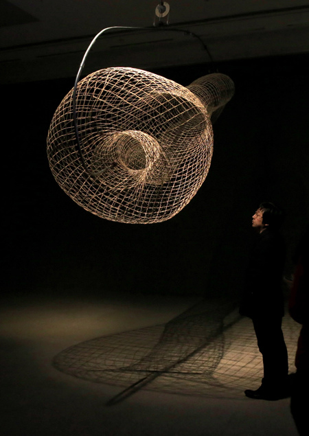 A visitor stops at Gimbaled Klein Basket by American artist Tim Hawkinson at the ongoing exhibition. Jiang Dong / China Daily