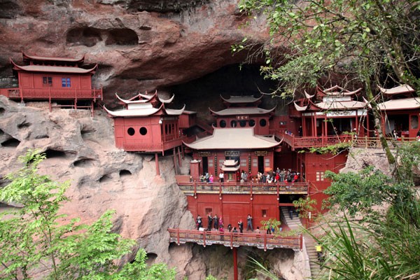 The spectacular Danxia landform in Taining, Fujian province, is a piece of art created by Mother Nature over a long time. Visitors can take in the natural beauty by cruising along the river on a bamboo raft or climbing the mountain to admire the ancient Ganlu Temple nestled inside a cave. Photos Provided to China Daily  