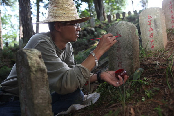 A worker repaints the inscription on a tombstone at the National Martyr Cemetery in Tengchong, Yunnan province. [Photo by Huo Yan/ China Daily]