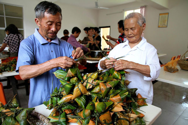 People make zongzi to welcome Dragon Boat Festival at a nursing home in Jing'an county,East China's Jiangxi province, June 8, 2013. [Photo/Xinhua]    