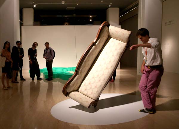 A vistor explores a couch at the exhibiton-Thing World at the National Art Museum in Beijing. [Photo by Jiang Dong/China Daily]  