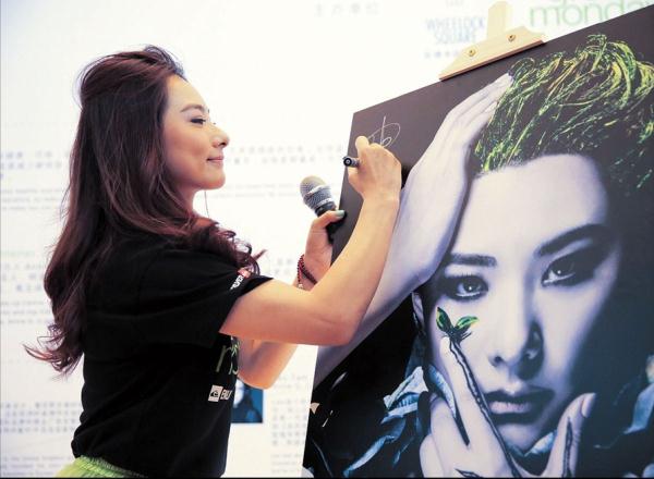 Former Olympic gymnastics champion Liu Xuan signs her name at the opening of the Enlighten Our Green Senses exhibition.