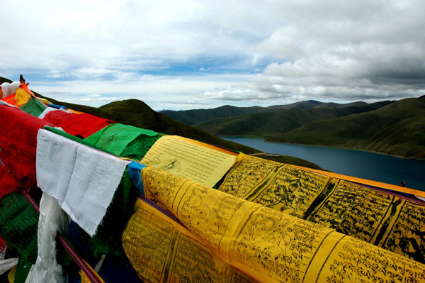 Colored prayer flags are attached to cliffs facing Yamdrok Co, one of the largest freshwater lakes in Tibet.
