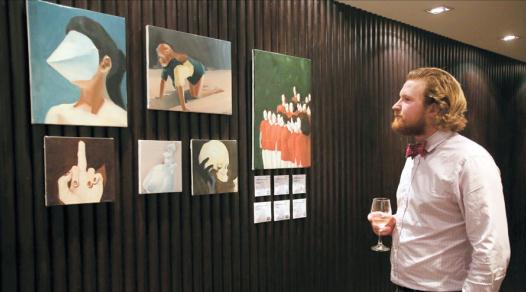 A man admires paintings by Chinese artists Meng Yangyang and Liu Na during Shanghai Dailys exhibition over a drink at CACHET Boutique Hotel.  Wang Rongjiang