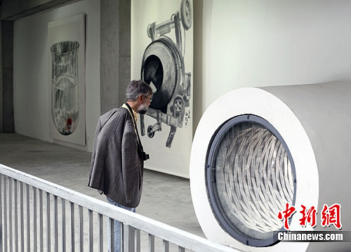 A visitor is appreciating paintings exhibited in Songzhuang art colony.[Photo/China News Service]