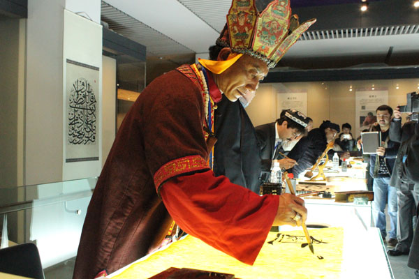 Dongba shaman He Guoyao demonstrates writing Dongba manuscripts at the Our Characteristics: Inheritance of Words in Intangible Cultural Heritage exhibition in Beijing. [Photo by Wang Kaihao/China Daily]
