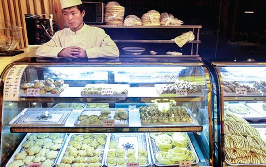 A staff member (above) sells traditional Xinjiang snacks at Kashgar Restaurant, a highly popular Beijing eatery that offers a variety of Xinjiang food including the famous roasted lamb leg (below). [Photo by Feng Yongbin / China Daily]  