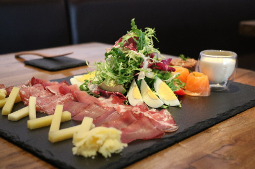 A platter features green salad, Australian beef tartare, strips of marinated Norwegian salmon and air-dried Swiss meats at Swiss Taste restaurant in Beijing.Photo by Hannah Adamson/For China Daily