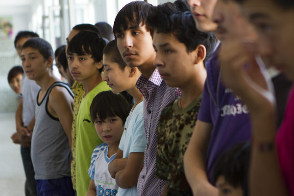 Vagrant children from Xinjiang rescued from criminal gangs and sent back to the region by the authorities in places where they had been coerced into stealing, stand in line waiting for assistance at a relief center in Urumqi, on Aug 4.
