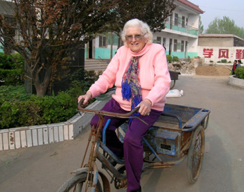 Eunice Moe Brock rides a tricycle in her home village. [photo: China Daily]