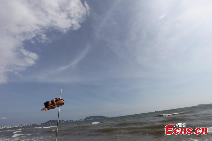 Fang Yi, member of China\'s national pole dancing team shows strength and beauty on a beach in China on Monday, September 15, 2014. China will host the 2015 World Pole Dance Championships in next April. [Photo/ Osports Photo Agency]