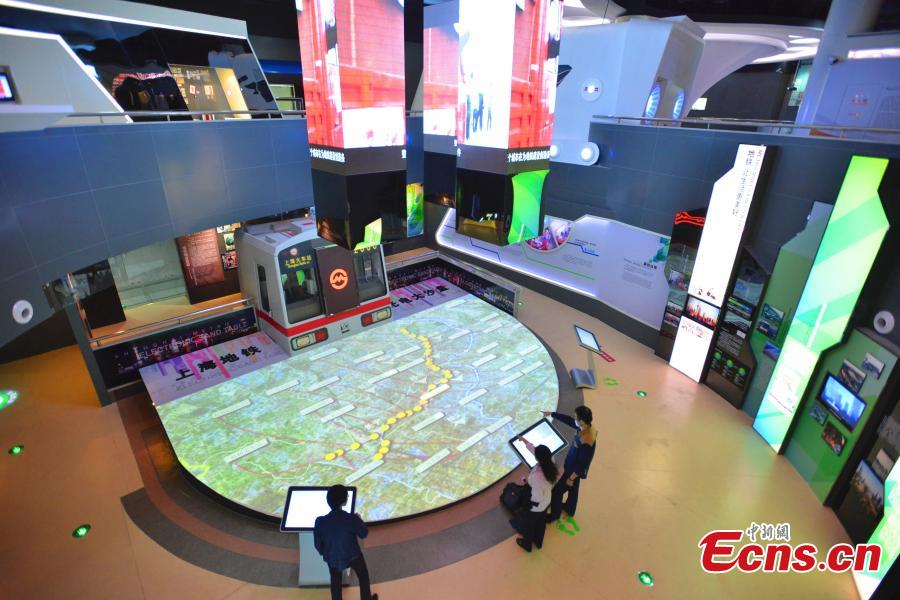 Visitors are attracted by a virtual sand table for Shanghai subway system at the newly-opened metro museum in Shanghai on Tuesday, October 28, 2014. As the first metro museum in the country, the attraction tells the history of the city’s subway and gives people the chance to experience the thrill of driving a subway train via a simulator. [Photo: China News Service/ Yuan Jing]