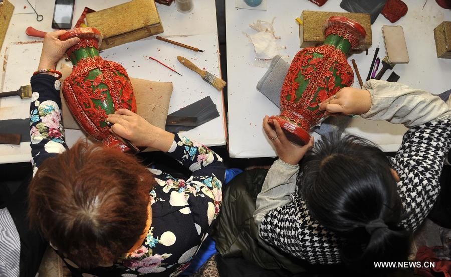 Craftsmen carve lacquerwares in a workshop in Gu\'an, north China\'s Hebei Province, Jan. 20, 2015. The Chinese traditional handicraft carved lacquerware, decorated with exquisite engravings and radiant with luster, was listed in the first batch of protection projects of national intangible cultural heritage in 2006. (Xinhua/Lu Peng)