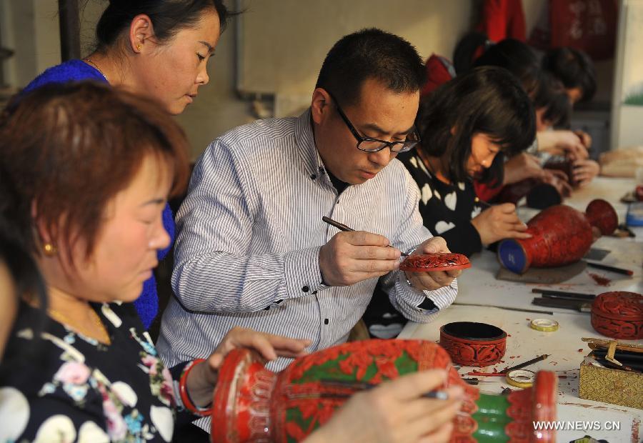 Craftsmen carve lacquerwares in the workshop in Gu\'an, north China\'s Hebei Province, Jan. 20, 2015. The Chinese traditional handicraft carved lacquerware, decorated with exquisite engravings and radiant with luster, was listed in the first batch of protection projects of national intangible cultural heritage in 2006. (Xinhua/Lu Peng)