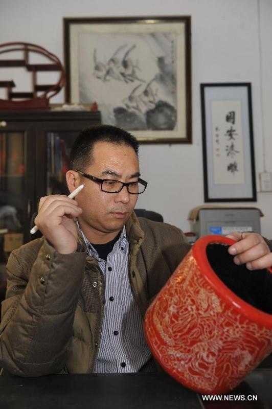 Craftsman Zhu Jiang designs a piece of carved lacquerware in his workshop in Gu\'an, north China\'s Hebei Province, Jan. 20, 2015. The Chinese traditional handicraft carved lacquerware, decorated with exquisite engravings and radiant with luster, was listed in the first batch of protection projects of national intangible cultural heritage in 2006. (Xinhua/Lu Peng)