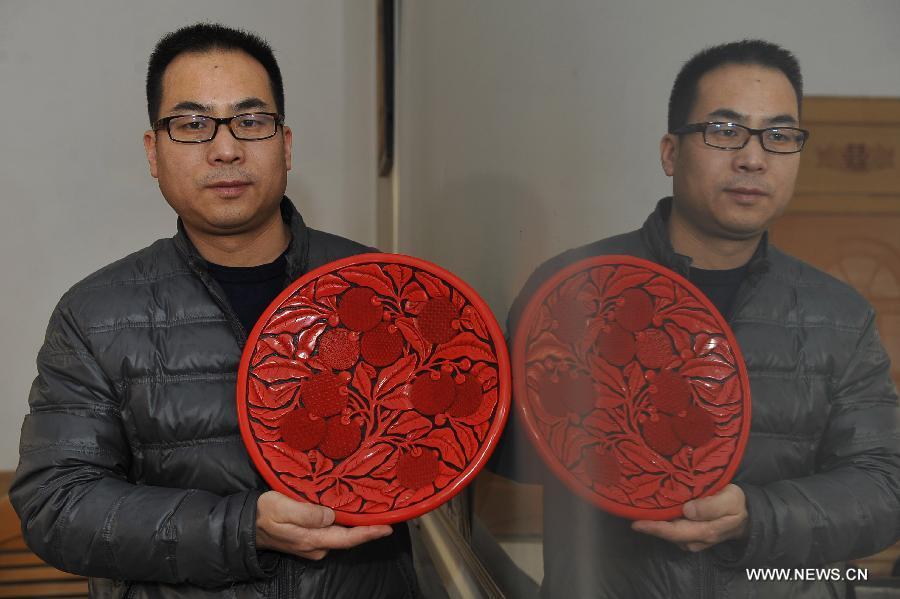 Craftsman Zhu Jiang holds a piece of carved lacquerware in his workshop in Gu\'an, north China\'s Hebei Province, Jan. 20, 2015. The Chinese traditional handicraft carved lacquerware, decorated with exquisite engravings and radiant with luster, was listed in the first batch of protection projects of national intangible cultural heritage in 2006. (Xinhua/Lu Peng)