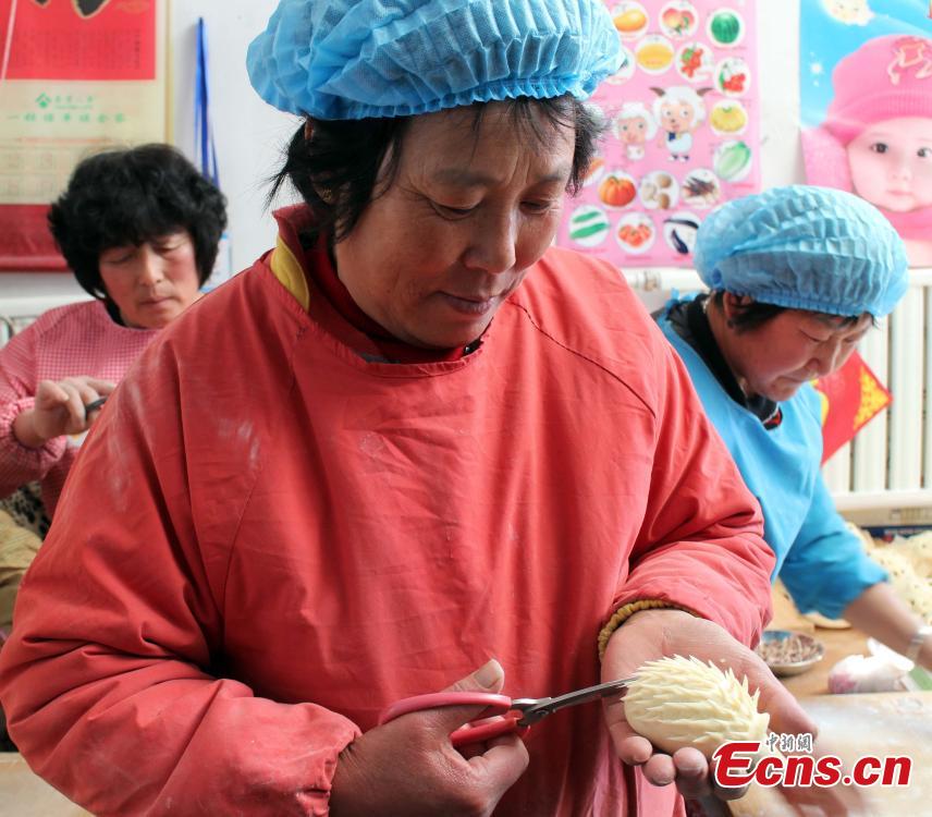 A woman makes a hedgehog-like steamed bun in Weihai, East China’s Shandong province, Feb 5, 2015. Local people have the tradition to make steamed buns with high-quality wheat flour, peanut oil, white sugar, eggs, and fresh milk before the Spring Festival, China’s Lunar New Year. The making of steamed buns reminds people of the process of becoming more and more prosperous. [Photo: China News Service/Liu Changyong]