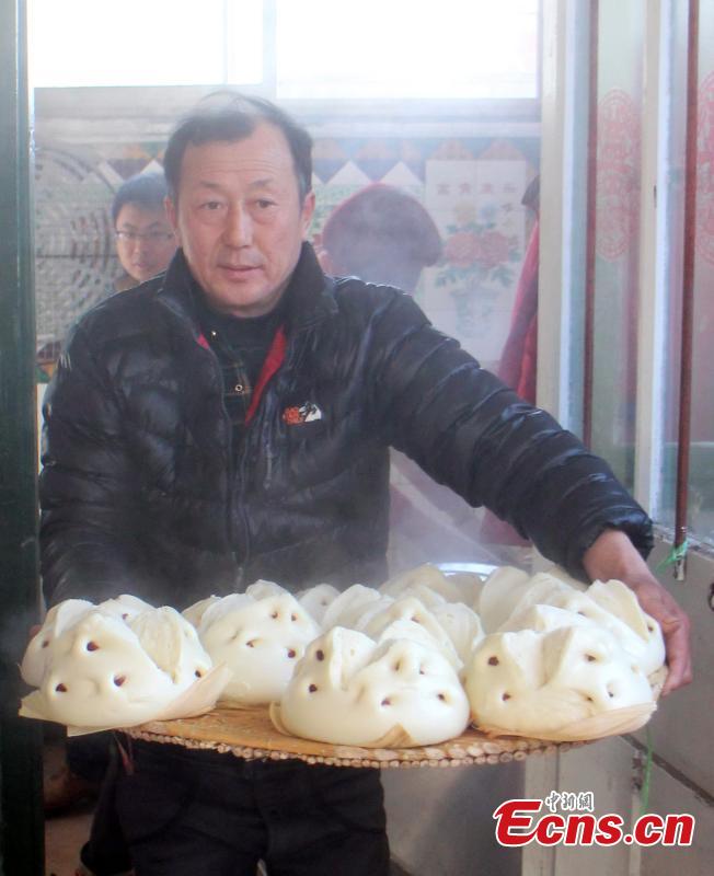 A man carries steamed buns stuffed with dates in Weihai, East China’s Shandong province, Feb 5, 2015. Local people have the tradition to make steamed buns with high-quality wheat flour, peanut oil, white sugar, eggs, and fresh milk before the Spring Festival, China’s Lunar New Year. The making of steamed buns reminds people of the process of becoming more and more prosperous. [Photo: China News Service/Liu Changyong]