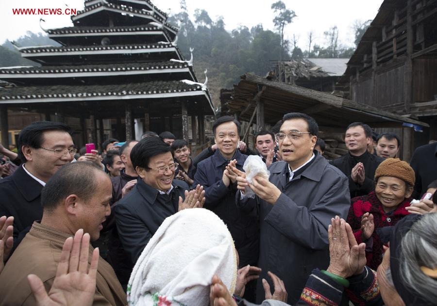 Chinese Premier Li Keqiang, also a member of the Standing Committee of the Political Bureau of the Communist Party of China (CPC) Central Committee, receives a piece of rice cake made by local villagers when finishing his visit in Pudong Village of Liping County, Qiandongnan Miao and Dong Autonomous Perfecture of southwest China\'s Guizhou Province, Feb. 13, 2015. Li made a tour in Qiandongnan Miao and Dong Autonomous Perfecture and Guiyang in Guizhou on Feb. 13 - 15, and extended festival greetings to locals and people of all ethnic groups ahead of the Spring Festival, which falls on Feb. 19. (Photo: Xinhua/Huang Jingwen)