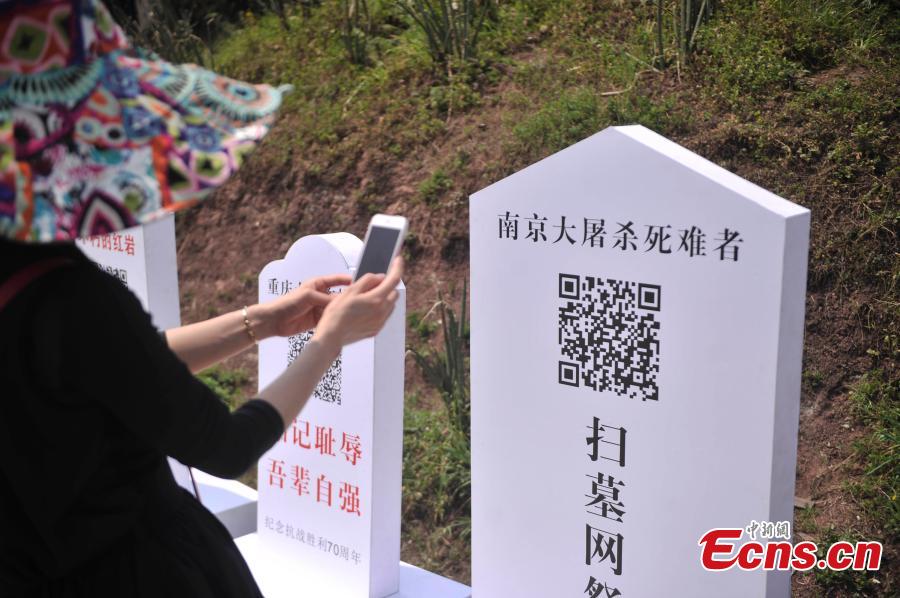 Visitors scan QR codes to commemorate victims of the Nanjing Massacre and Bombing of Chongqing, both committed by Japanese troops in China during World War II, at the theme park Foreigner Street in Southwest China’s Chongqing municipality, March 31, 2015. Visitors can take part in an online memorial, by lighting candles, presenting flowers, ringing bells and planting trees. (Photo: China News Service/Chen Chao)
