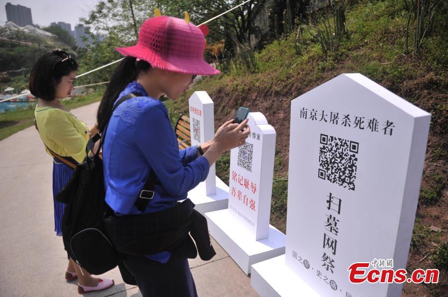 Visitors scan QR codes to commemorate victims of the Nanjing Massacre and Bombing of Chongqing, both committed by Japanese troops in China during World War II, at the theme park Foreigner Street in Southwest China’s Chongqing municipality, March 31, 2015. Visitors can take part in an online memorial, by lighting candles, presenting flowers, ringing bells and planting trees. (Photo: China News Service/Chen Chao)