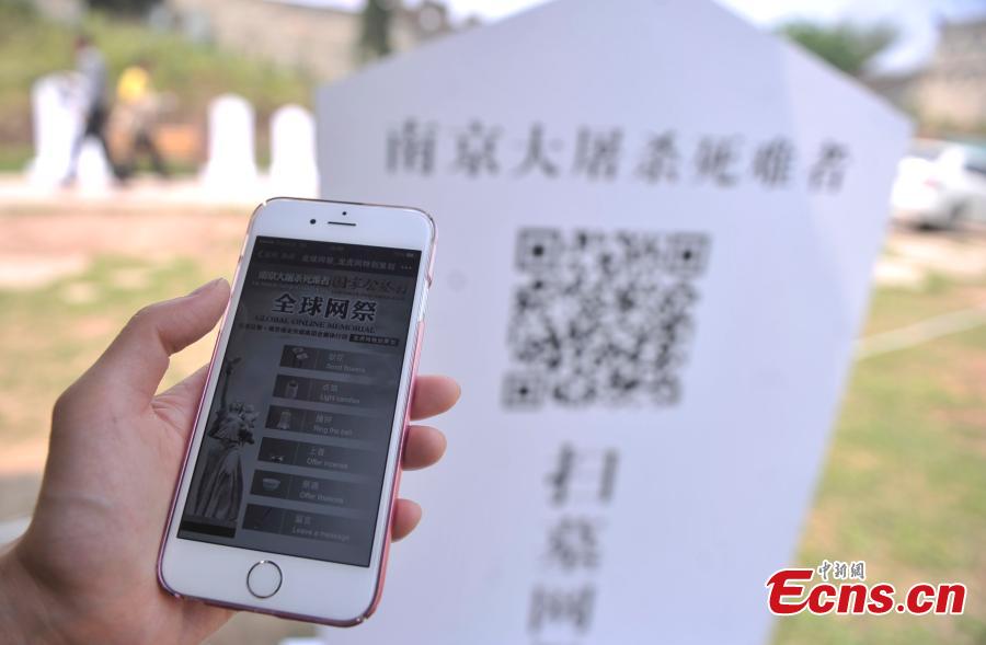 A visitor scans a QR code to commemorate victims of the Nanjing Massacre and Bombing of Chongqing, both committed by Japanese troops in China during World War II, at the theme park Foreigner Street in Southwest China’s Chongqing municipality, March 31, 2015. Visitors can take part in an online memorial, by lighting candles, presenting flowers, ringing bells and planting trees. (Photo: China News Service/Chen Chao)