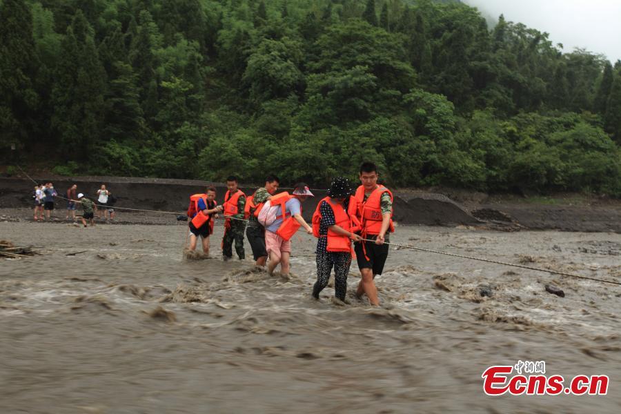 Rescuers help evacuate hikers stranded by rising floodwaters after rainstorms in a valley in Southwest China’s Chongqing municipality, June 1, 2015. A total of 18 tourists, including six children, were trapped by floods and later saved by rescuers. (Photo: China News Service/Huang Xing)