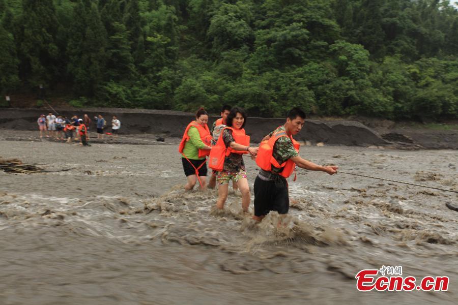 Rescuers help evacuate hikers stranded by rising floodwaters after rainstorms in a valley in Southwest China’s Chongqing municipality, June 1, 2015. A total of 18 tourists, including six children, were trapped by floods and later saved by rescuers. (Photo: China News Service/Huang Xing)