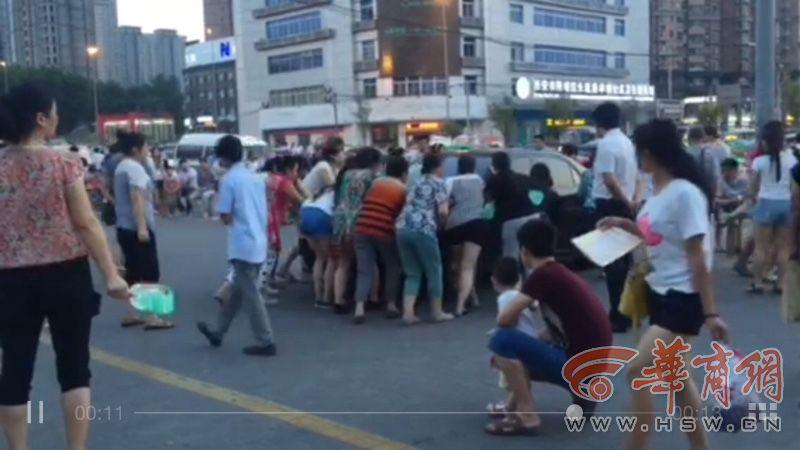 More than ten middle-aged women are seen pushing a car parked on the road in Xi\'an, in northwestern China, on 22nd July, 2015. Three cars were reportedly moved successively. The women turned out to be enthusiasts of the evening line dance, known in China as \