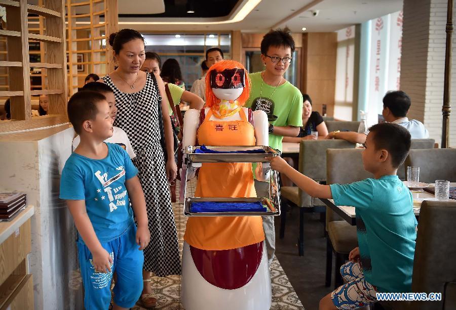 Customers look at the robot waiter in Haikou, capital of south China\'s Hainan Province, Aug. 3, 2015. A robot waiter was introduced to a restaurant in Haikou. (Photo: Xinhua/Guo Cheng)