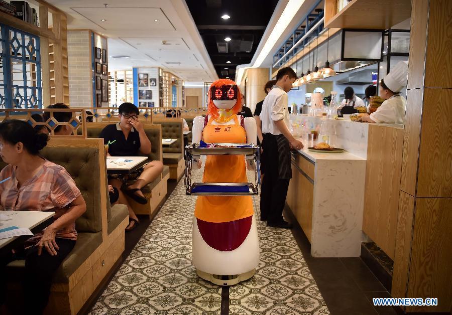 The robot waiter delivers dishes in Haikou, capital of south China\'s Hainan Province, Aug. 3, 2015. A robot waiter was introduced to a restaurant in Haikou. (Photo: Xinhua/Guo Cheng)