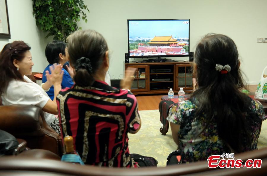 Overseas Chinese watch the broadcasting of commemoration activities to mark the 70th anniversary of the victory of the Chinese People\'s War of Resistance Against Japanese Aggression and the World Anti-Fascist War, on TV in Los Angeles, the United States, Sept. 2, 2015. (CNS photo/Mao Jianjun)