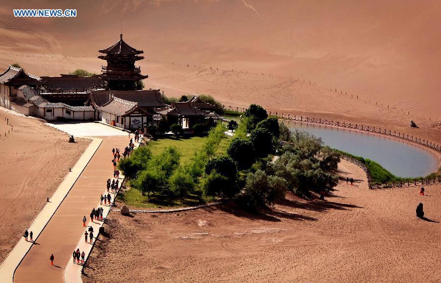 Photo taken on May 23, 2015 shows people visiting the crescent spring of the Mingsha Hill in Dunhuang of northwest China\'s Gansu Province. Desert Tourism in northwest China attracts a large number of tourists from home and abroad.  (Photo: Xinhua/Wang Song)