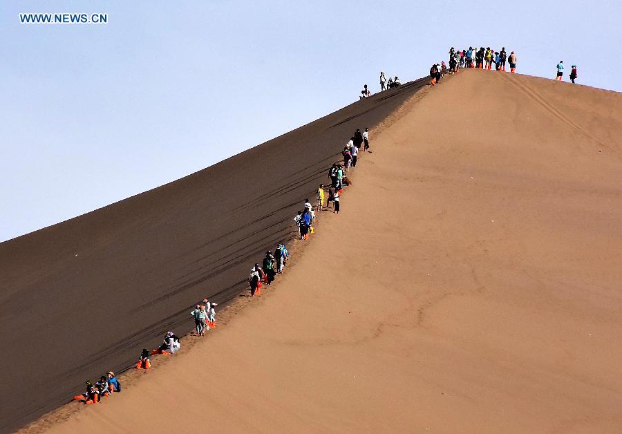 Photo taken on May 23, 2015 shows people visiting the Mingsha Hill in Dunhuang of northwest China\'s Gansu Province. Desert Tourism in northwest China attracts a large number of tourists from home and abroad. (Photo: Xinhua/Wang Song)