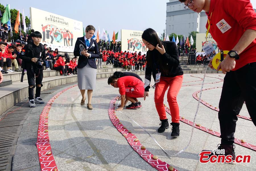 Students and charity workers display envelopes containing prayer cards in a heart shape in Zhejiang Chinese Medicine University in Hangzhou, East China\'s Zhejiang province, on Monday. The event, to raise funds for students in poverty-stricken areas of China, will see the envelopes posted to students and volunteers to pass on the spirit of charity. The envelop chain, reaching 335.23 meters in length, set a new Guinness World Record for the longest envelope chain. (Photo/CFP)