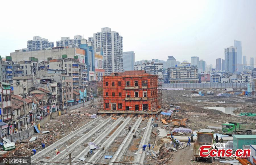 A historic building listed as a cultural relic under government protection is moved as a whole unit in Wuhan City, the capital of Central China’s Hubei Province, March 9, 2016. The three-storeyed, 100-year-old building was first raised 1.4 meters off the ground and then supported by scaffolding in order to move it for 90 meters on six reinforced-concrete tracks. The site is being cleared for a commercial development, local media reported. (Photo/CFP)