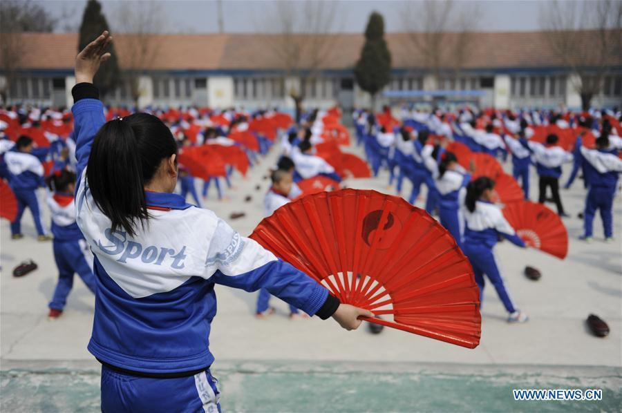 Pupils of Foyelai Primary School exercise with Taiji fans in Xinglong County of Chengde City, north China\'s Hebei Province, March 16, 2016. Students in Xinglong County learn traditional Chinese martial art, diabolo exercising and Hulusi performance during their spare time. (Photo: Xinhua/Wang Liqun)