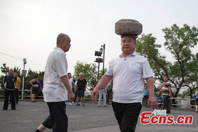 Man exercises with heavy cement block on head(1/4)