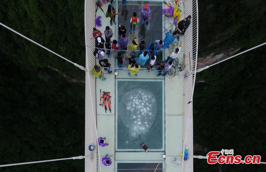 Visitor strike the glass-bottomed bridge with hammers for a safety test at Zhangjiajie Grand Canyon on June 25, 2016 in Zhangjiajie, Hunan Province of China. The bridge is 430 meters long, six meters wide and 300 meters above the valley. (Photo: China News Service/ Yang Huafeng)
