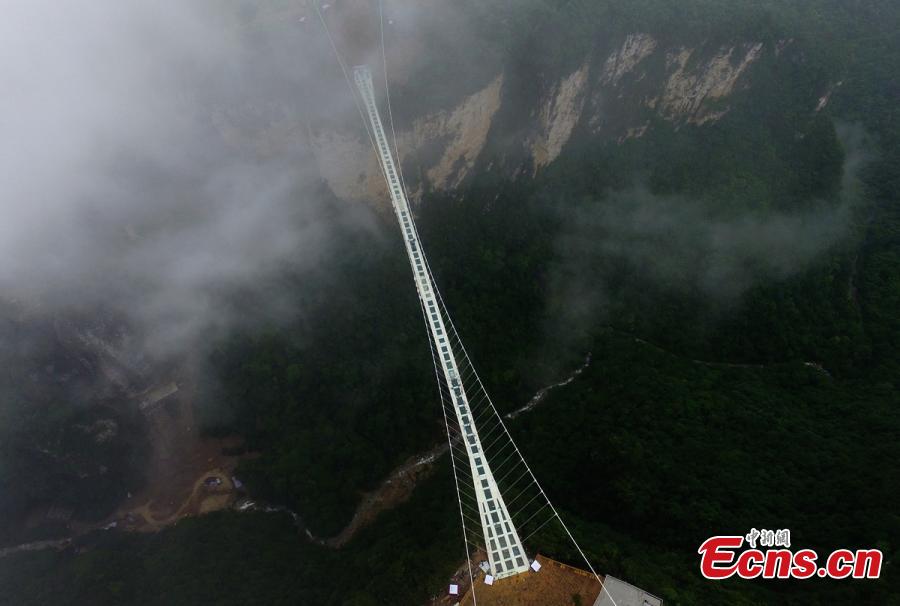 A SUV travels on a glass bridge during a load testing at the Grand Canyon of Zhangjiajie, central China\'s Hunan Province, June 25, 2016. The bridge is 430 meters long, six meters wide and 300 meters above the valley. (Photo: China News Service/ Yang Huafeng)