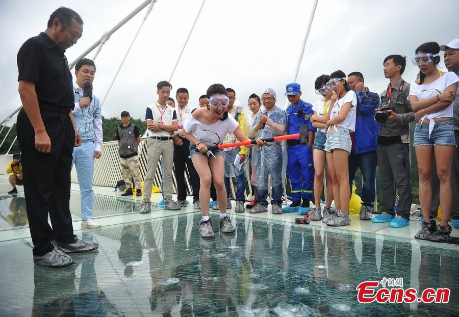 Visitor strike the glass-bottomed bridge with hammers for a safety test at Zhangjiajie Grand Canyon on June 25, 2016 in Zhangjiajie, Hunan Province of China. The bridge is 430 meters long, six meters wide and 300 meters above the valley. (Photo: China News Service/ Yang Huafeng)