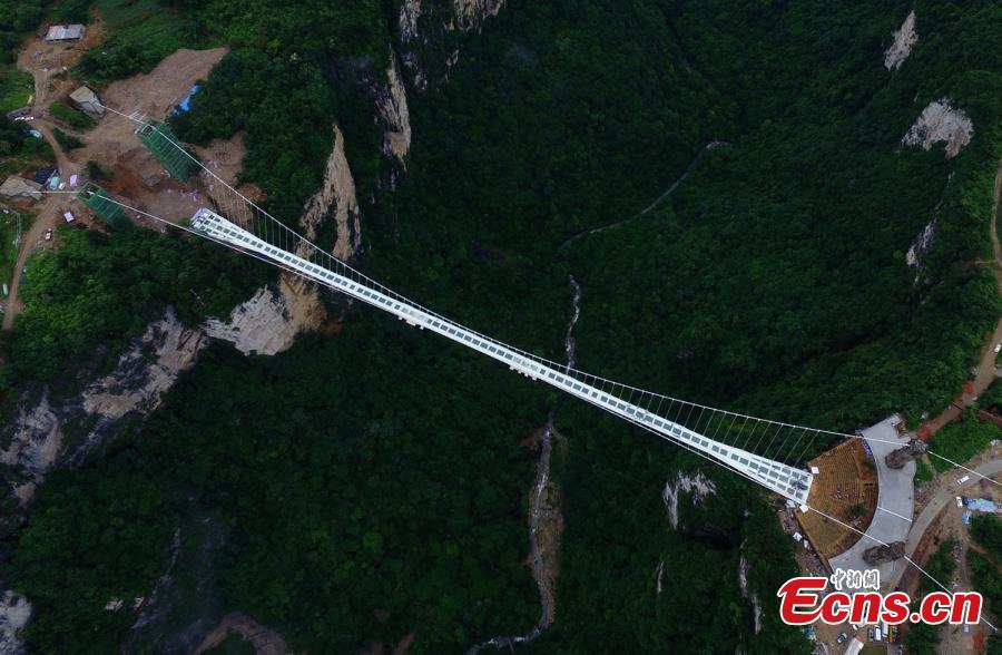 A SUV travels on a glass bridge during a load testing at the Grand Canyon of Zhangjiajie, central China\'s Hunan Province, June 25, 2016. The bridge is 430 meters long, six meters wide and 300 meters above the valley. (Photo: China News Service/ Yang Huafeng)