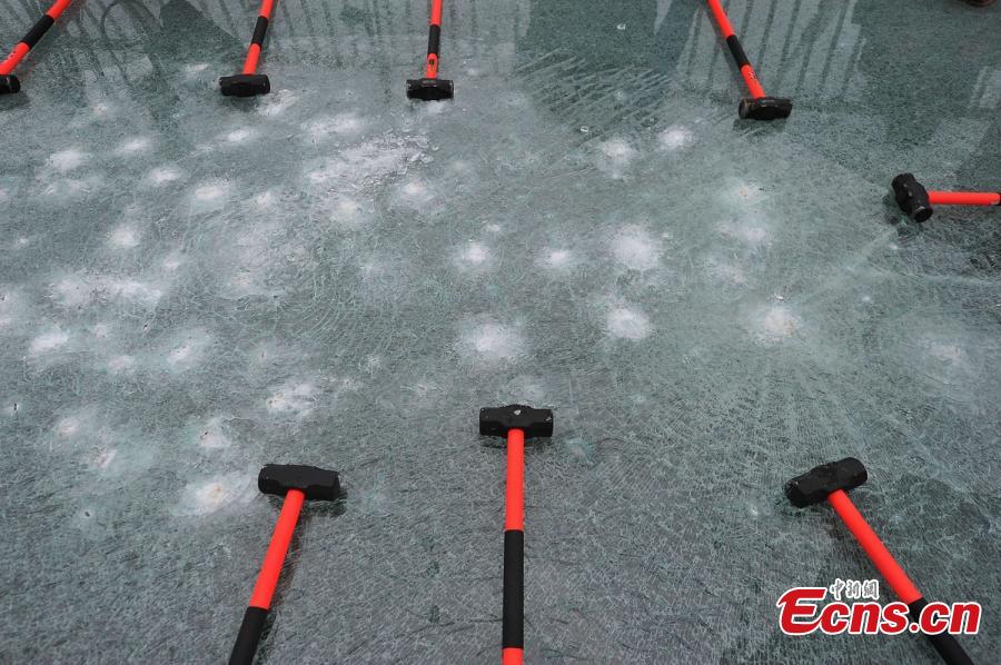 Visitor strike the glass-bottomed bridge with hammers for a safety test at Zhangjiajie Grand Canyon on June 25, 2016 in Zhangjiajie, Hunan Province of China. The bridge is 430 meters long, six meters wide and 300 meters above the valley. (Photo: China News Service/ Yang Huafeng)