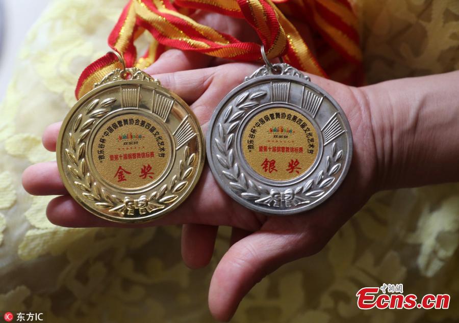 Zhang Jing, 53, shows her medals for pole dancing in Zhengzhou City, the capital of Central China’s Henan Province. Zhang had to retire two years ago when the state-owned company she worked for became bankrupt. Supported by her son, a dance trainer at a gym, Zhang started learning yoga before falling in love with pole dancing, usually working out with women about 30 years younger than her. Despite her age, Zhang practices hard and tries challenging body movements. In a recent pole dance championship in Beijing, she avoided the seniors age group, and still won one gold medal and one silver medal in the middle-age group. Zhang is not only able to keep in shape but has become a role model to others. She says nothing is too late to start if only a person has a dream. (Photo/IC)