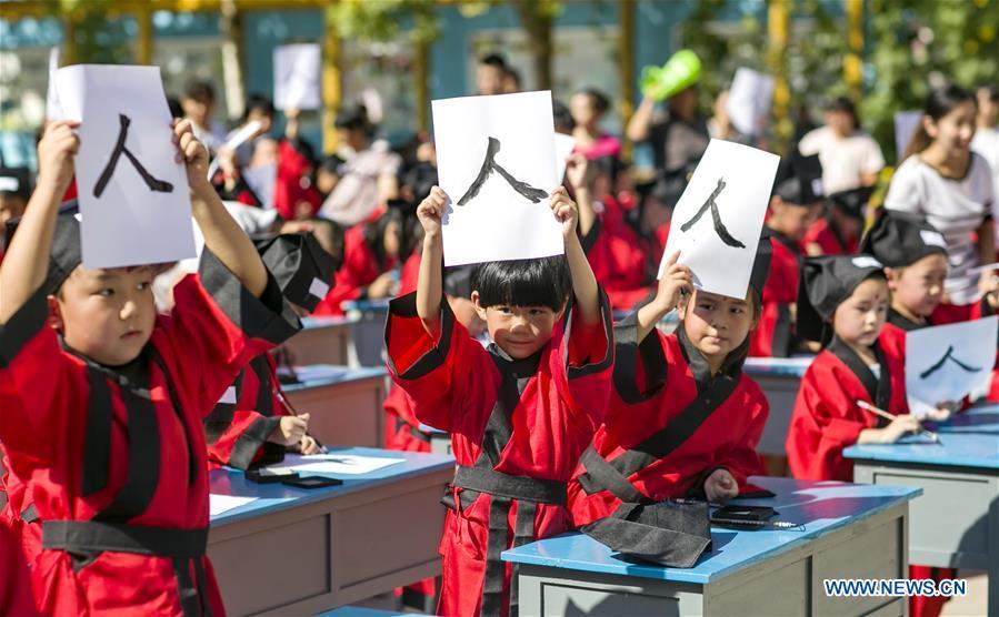 Children show their calligraphy at the first writing ceremony in Zhixing Elementary School in Qiaoxi District under Xingtai, north China\'s Hebei Province, Aug. 31, 2016. More than 200 children wearing Han-style costume, or Hanfu attended the ceremony, a traditional education activity for children to start their school life in China, in Xingtai Wednesday. (Photo/Xinhua)