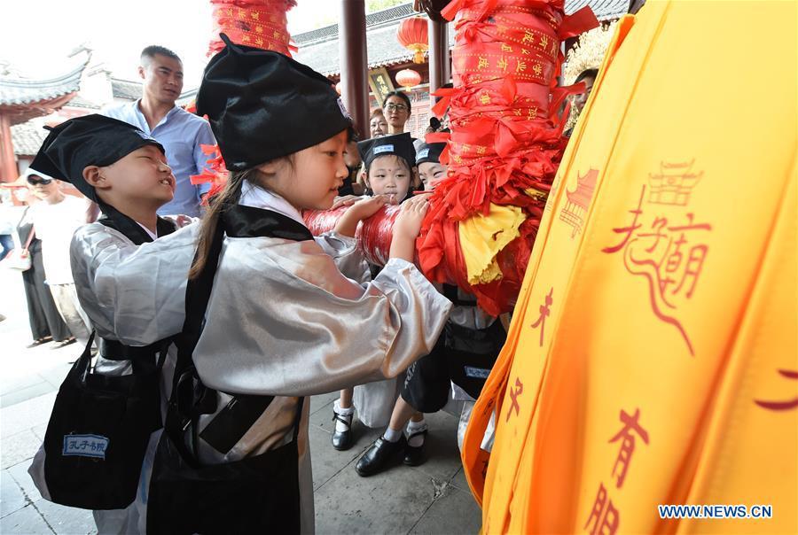 Children strike a bell at the first writing ceremony in Nanjing, capital of east China\'s Jiangsu Province, Aug. 31, 2016. A total of 168 children attended the ceremony, a traditional education activity for children to start their school life in China, at the Confucius Temple in Nanjing on Wednesday. (Photo/Xinhua)