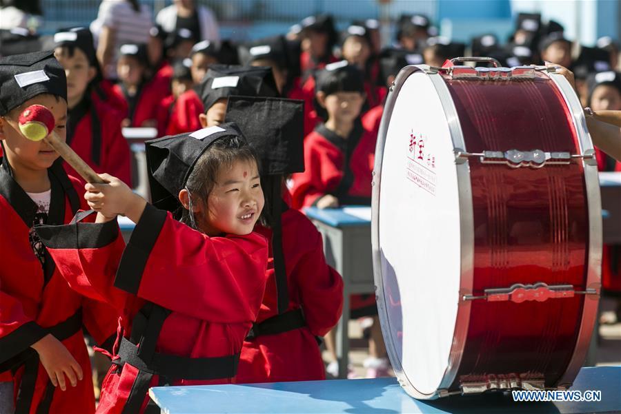 A child beats a drum at the first writing ceremony in Zhixing Elementary School in Qiaoxi District under Xingtai, north China\'s Hebei Province, Aug. 31, 2016. More than 200 children wearing Han-style costume, or Hanfu attended the ceremony, a traditional education activity for children to start their school life in China, in Xingtai Wednesday. (Photo/Xinhua)