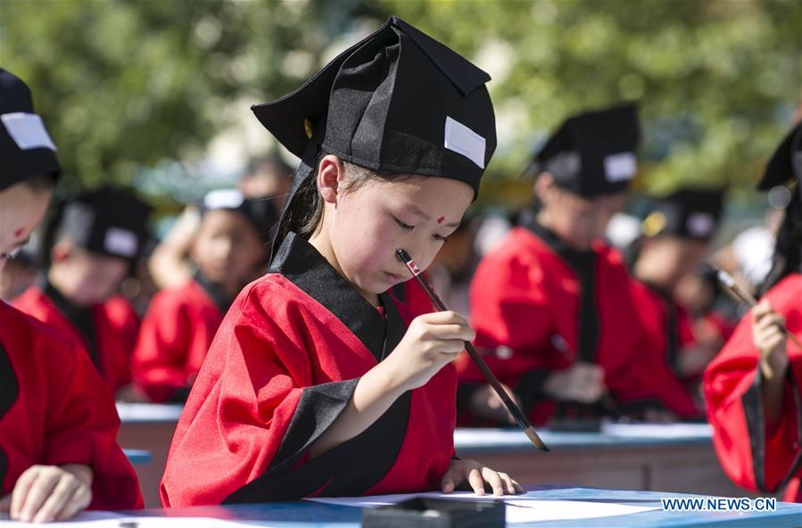 Children write calligraphy at the first writing ceremony in Zhixing Elementary School in Qiaoxi District under Xingtai, north China\'s Hebei Province, Aug. 31, 2016. More than 200 children wearing Han-style costume, or Hanfu attended the ceremony, a traditional education activity for children to start their school life in China, in Xingtai Wednesday. (Photo/Xinhua)