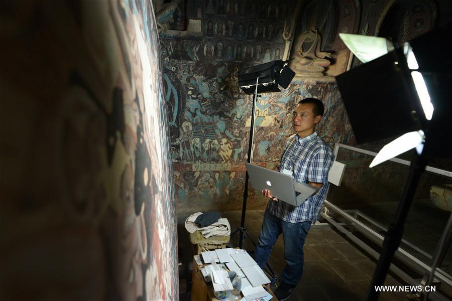 Chen Haitao, a member of the designing team with the Dunhuang Academy, works at Cave No. 254 in Mogao Grottoes, Dunhuang, northwest China\'s Gansu Province, Sept. 18, 2016. Dunhuang Academy has been working on making animated shows out of ancient Dunhuang murals using modern digital media in recent years. Two films based on murals in Cave No. 254 of Mogao Grottoes have been completed. (Photo/Xinhua)